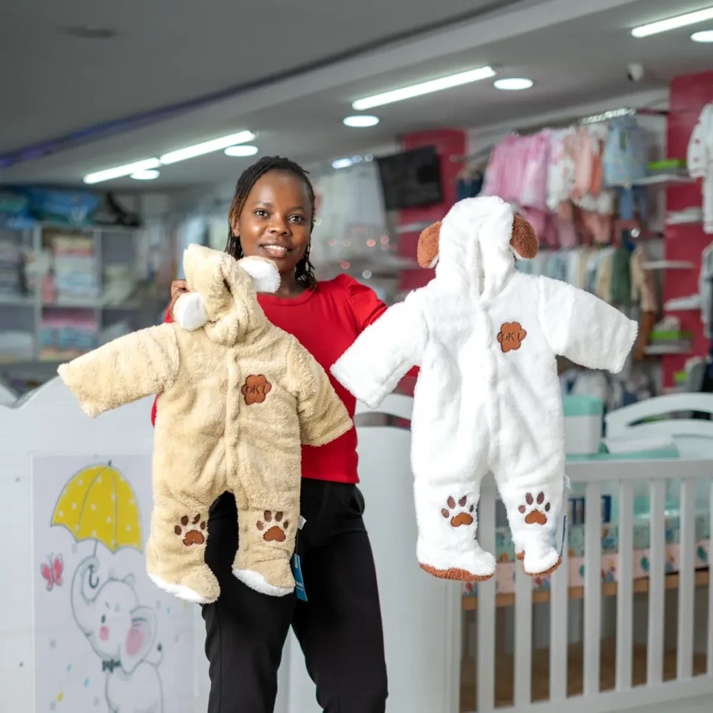Two warm hooded baby rompers held up in the shop at Zawadi Baby Shop Nairobi.