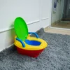 3-In-1 Potty Training System With Music 1 Angled View Of The Colorful Child'S Potty Chair (Red Base, Yellow Seat, Blue Handles, Open Green Lid) Sitting On A Gray Shag Carpet Near A White Wall And A Glimpse Of A Doorway.
