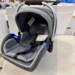 Dark grey Kidilo carrycot car seat with a modern design, padded interior, and safety features, perfect for infant travel, shown at Zawadi Baby Shop.