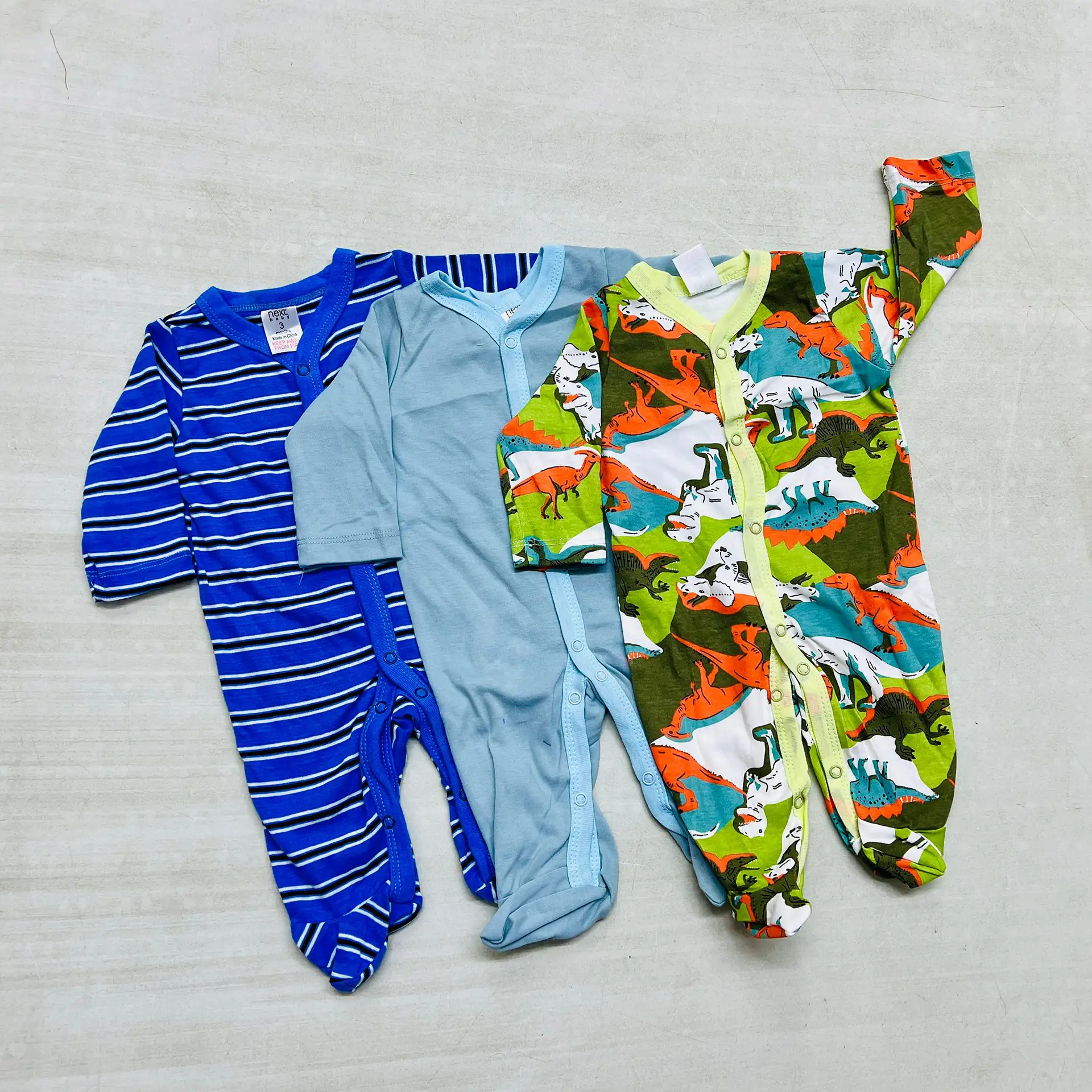 Cotton Rompers 3Pcs Set 8 A Set Of Three Cotton Baby Rompers In Blue Stripes, Solid Light Blue, And Dinosaur Print, Featuring Snap Closures And Soft Fabric For Comfort.