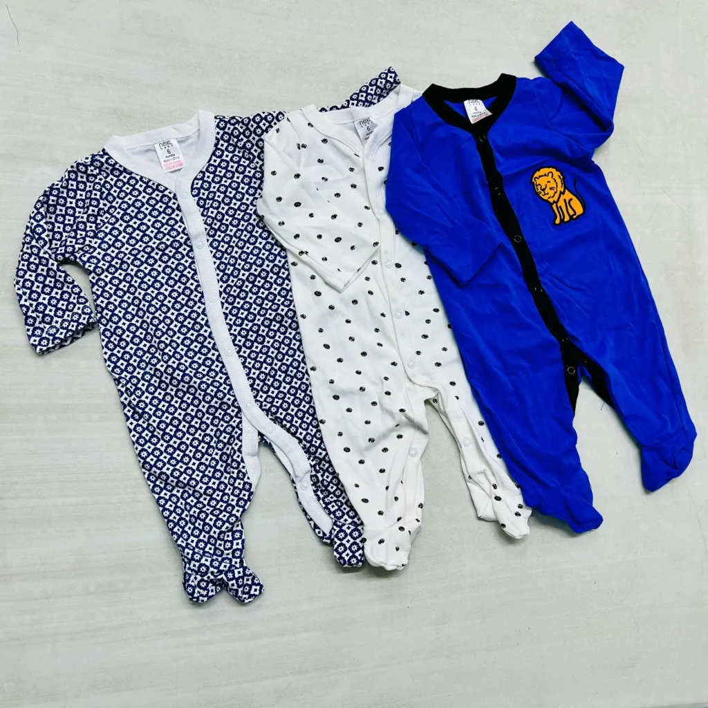 A pack of three cotton baby rompers in navy geometric print, white polka dots, and solid blue with a lion patch, designed for comfort and easy wear.