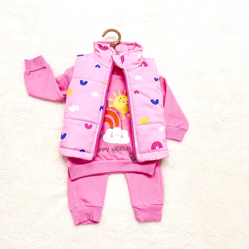 A baby girl's bright pink outfit including a long-sleeve sweatshirt, matching pants, and a sleeveless pink puffer vest adorned with colorful rainbows, clouds, and sunshine illustrations. The sweatshirt reads 'Happy World' with a cheerful sun and rainbow print.