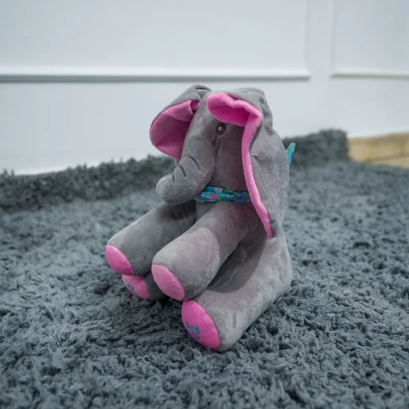 Plush gray elephant soft toy with pink ears and feet, sitting on a soft gray rug—ideal for babies and toddlers, available at Zawadi Baby Shop.