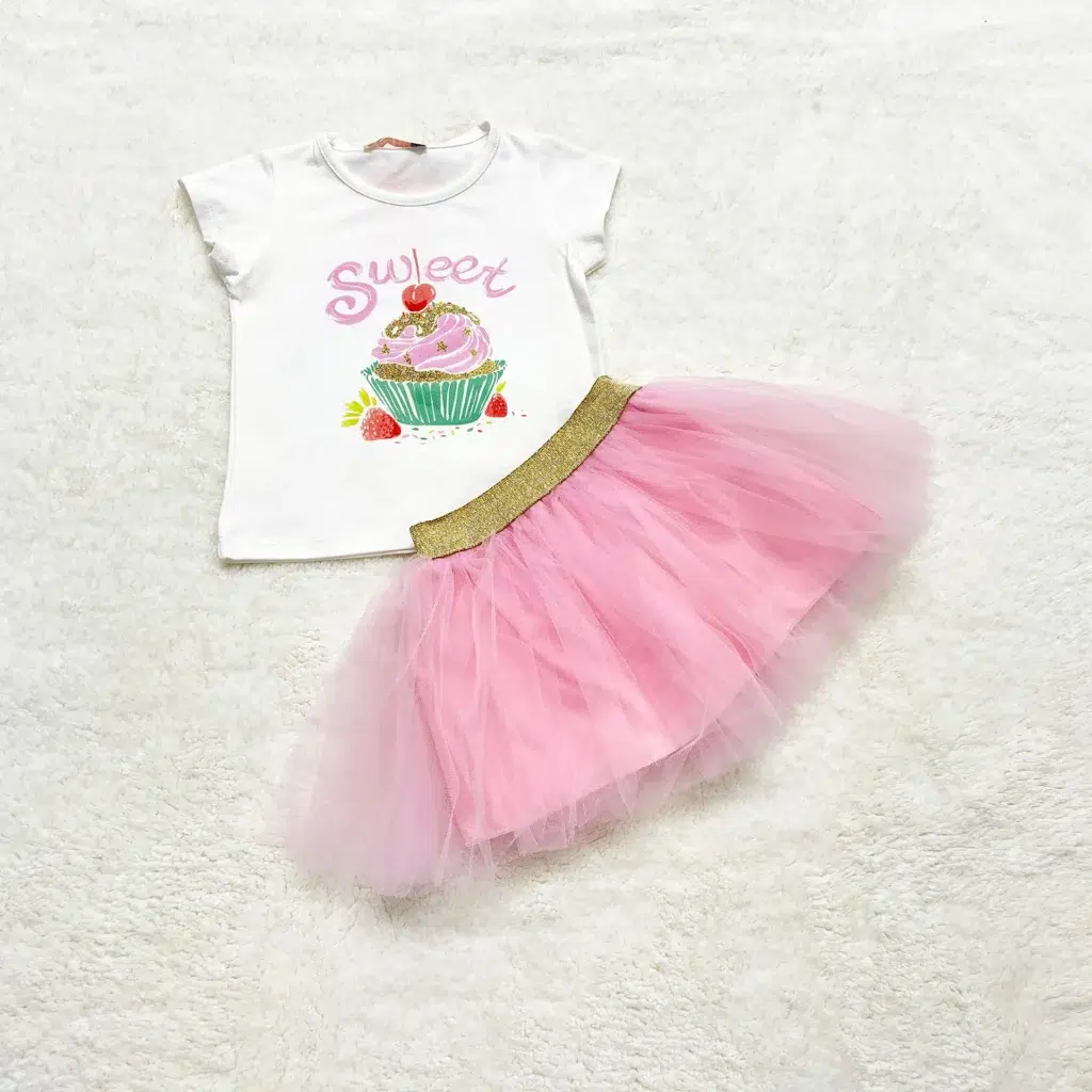 White short-sleeve t-shirt with a cupcake and “Sweet” text in pink, paired with a bright pink tulle skirt with a gold elastic waistband.