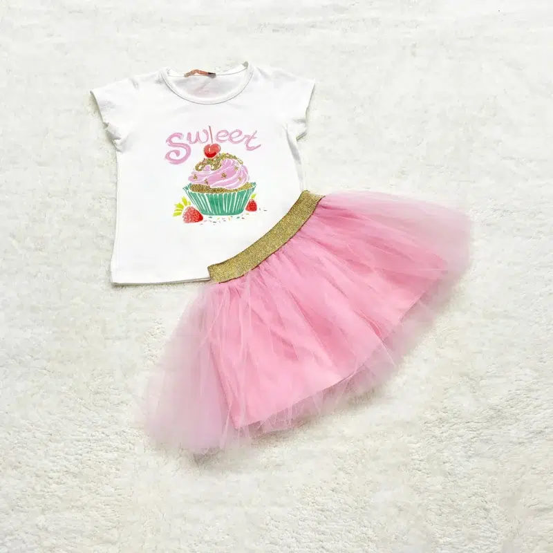 White short-sleeve t-shirt with a cupcake and “Sweet” text in pink, paired with a bright pink tulle skirt with a gold elastic waistband.