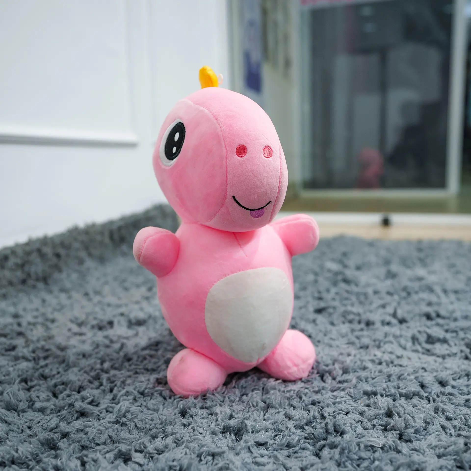 Plush Soft Toy 3 Pink Plush Soft Toy With A White Belly And Friendly Face, Displayed On A Grey Carpet In A Nursery Setting – Ideal For Babies And Toddlers.